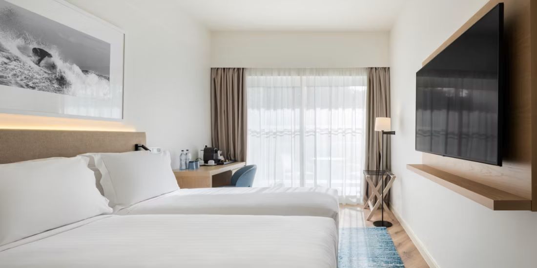 Twin beds with large window in the room at Crowne Plaza Caparica