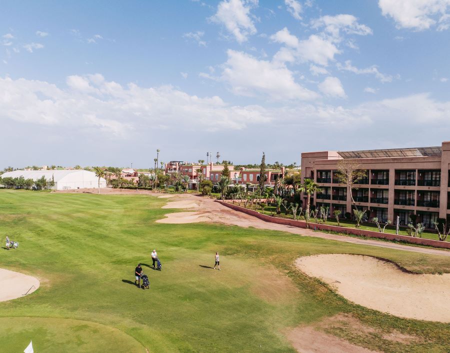 Pickalbatros Hotel Du Golf Palmeraie Marrakech with golf course next to it, with sand bunkers and two golfers on the fairway