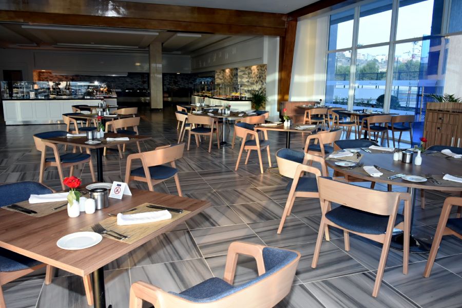Dining area with tables set for service and views out from large windows at Tariq Lamptey