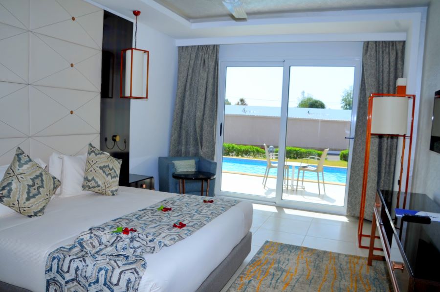Double bed with chair in corner and patio doors at Pickalbratros White Beach Taghazout Resort