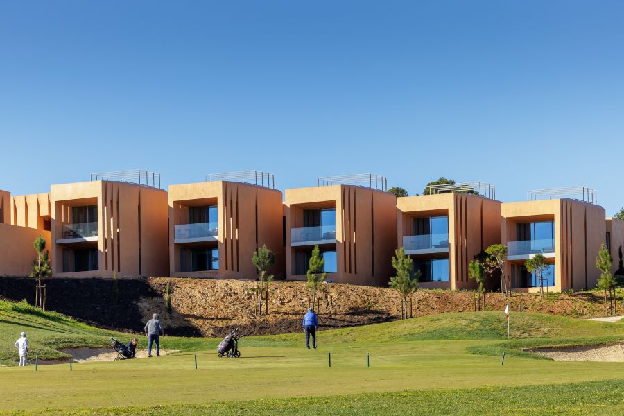 Blue sky over the course where golfers are on the fairway at Palmares Signature Apartments