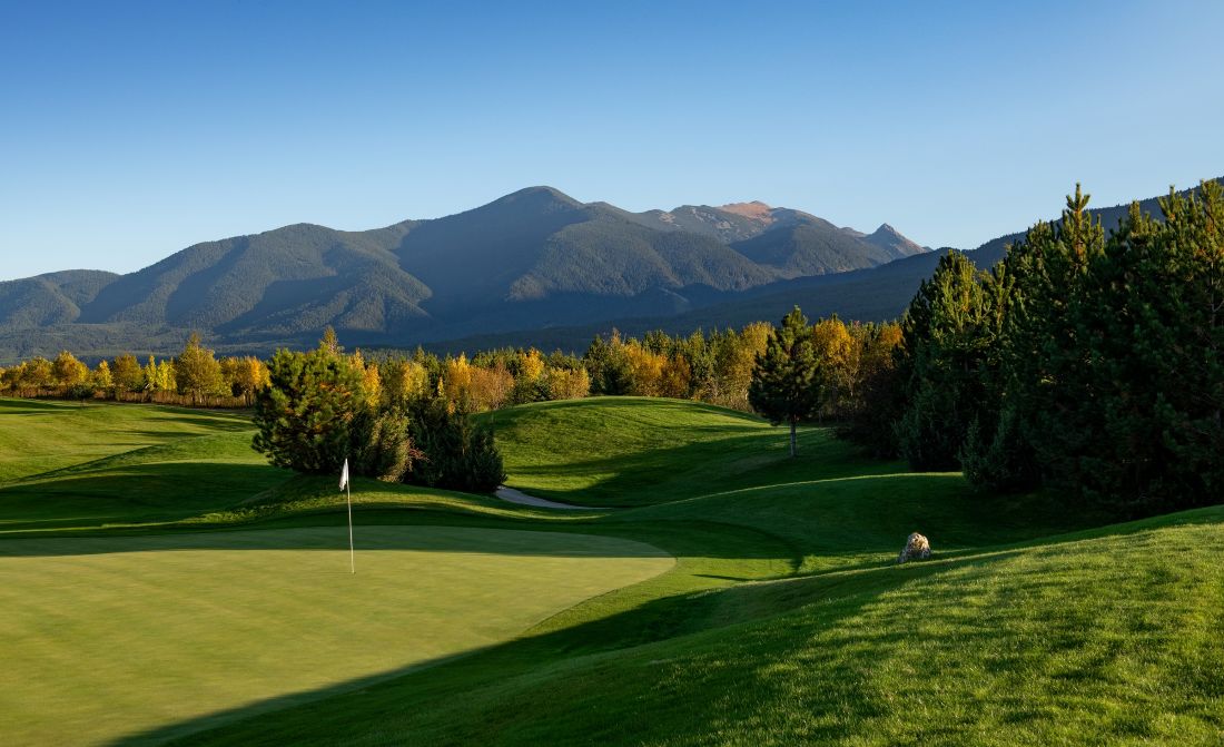 Trees surrounding Pirin Golf with flag on the left