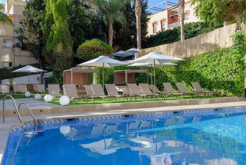 Sun loungers and parasols next to the swimming pool at Hotel Costa Malaga