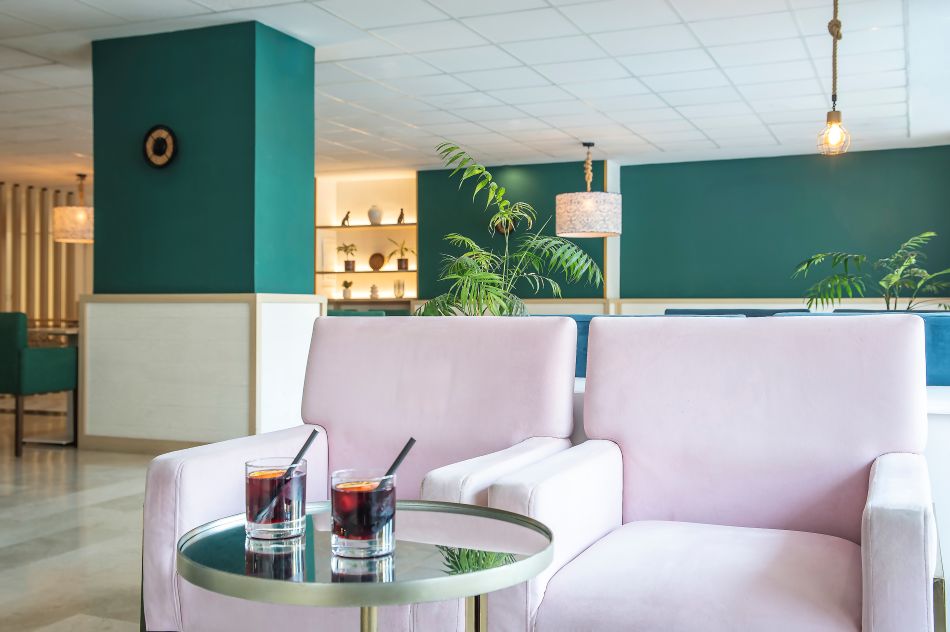 Bar with green walls and pink chairs at Hotel Costa Malaga