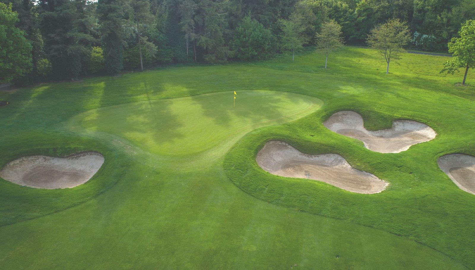 Flag on putting green with trees in the background and bunkers to the right at Killeen Castle golf course in Ireland