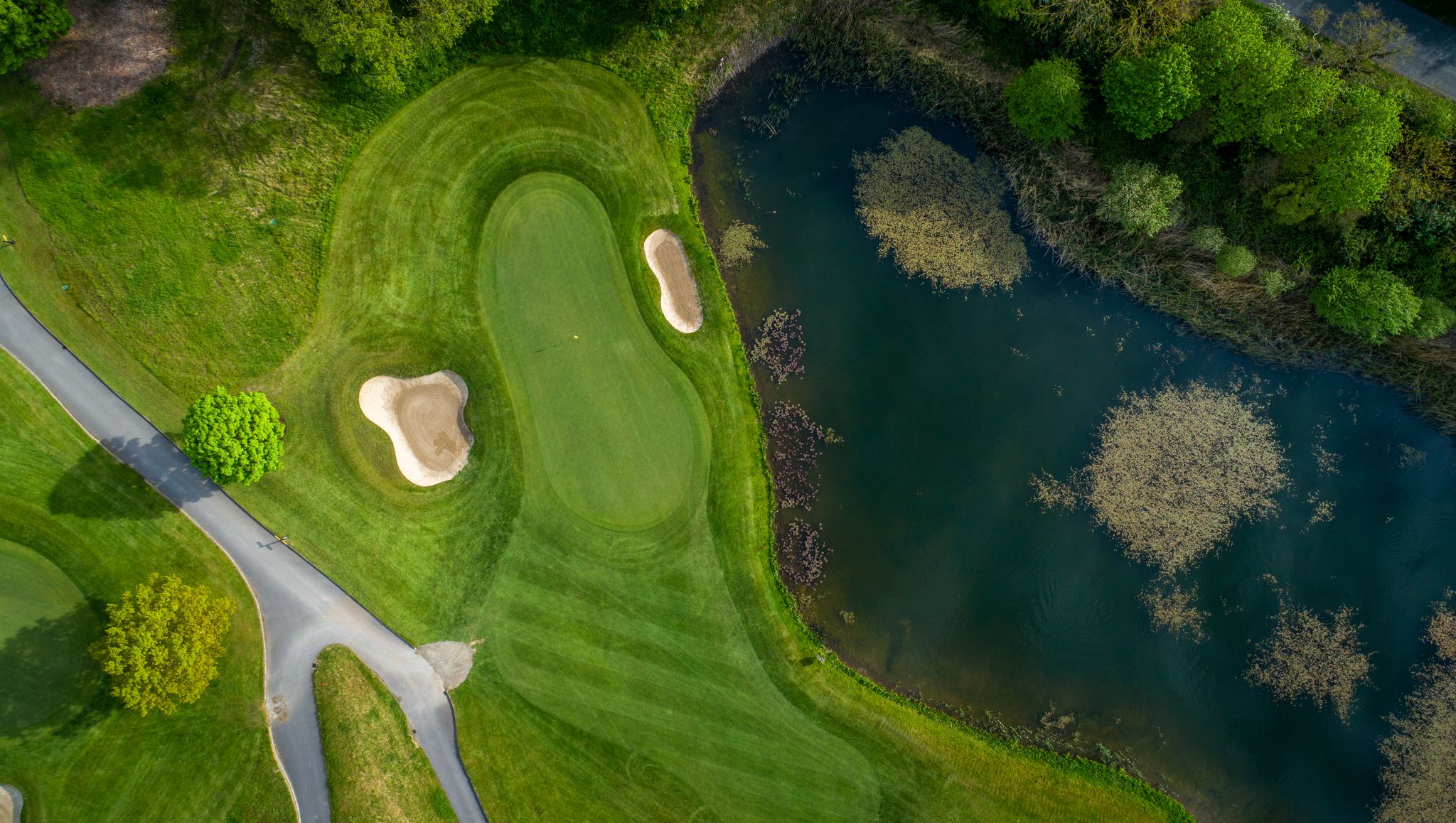 Putting green protected by sand bunkers, with lake to the right of the golf course at Killeen Castle golf course in Ireland