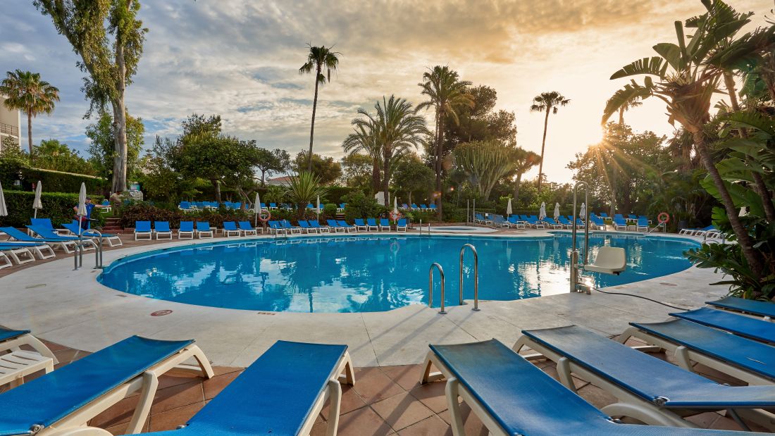 Swimming pool at Hotel Palmasol with palm trees and sun loungers